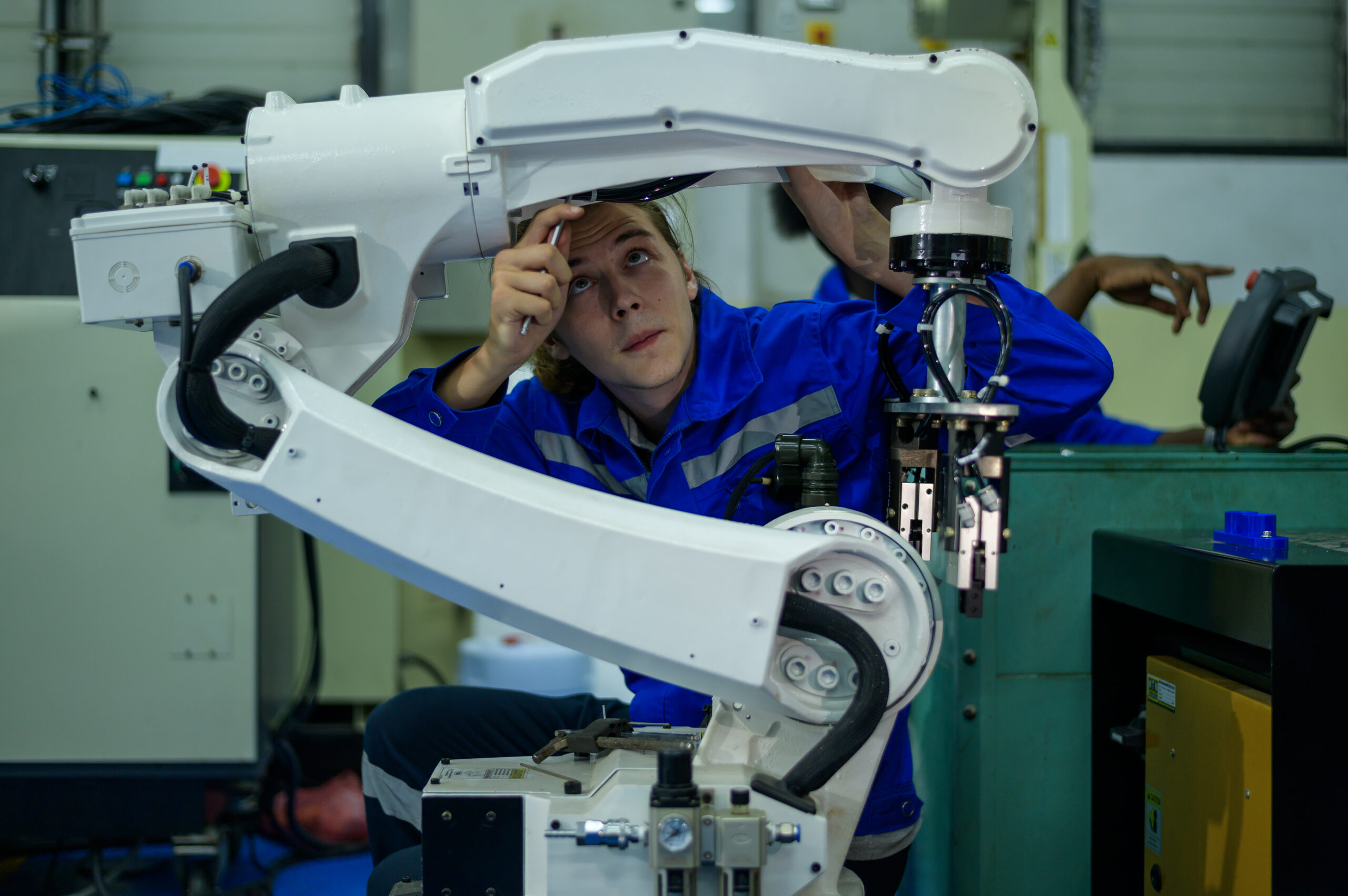 Male Robotics engineer working with Programming and Manipulating Robot Hand, Industrial Robotics Design, High Tech Facility, Modern Machine Learning. Mass Production Automatics